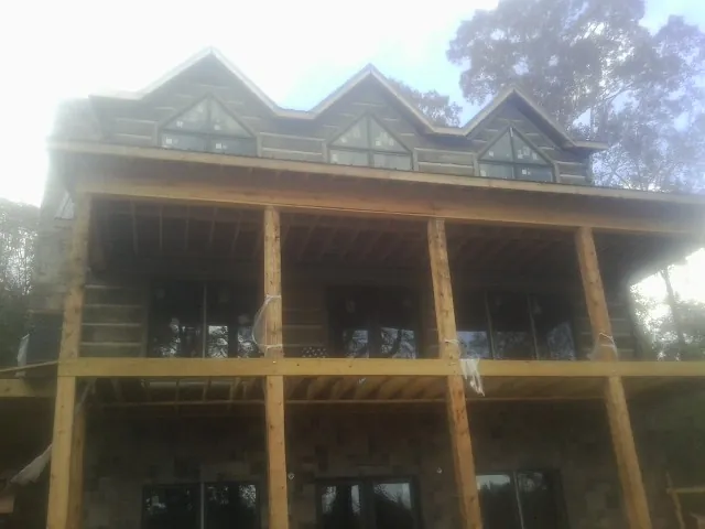 Dormers and porch framing on a large log home under construction — Roof Coating work by our crew in Stanley