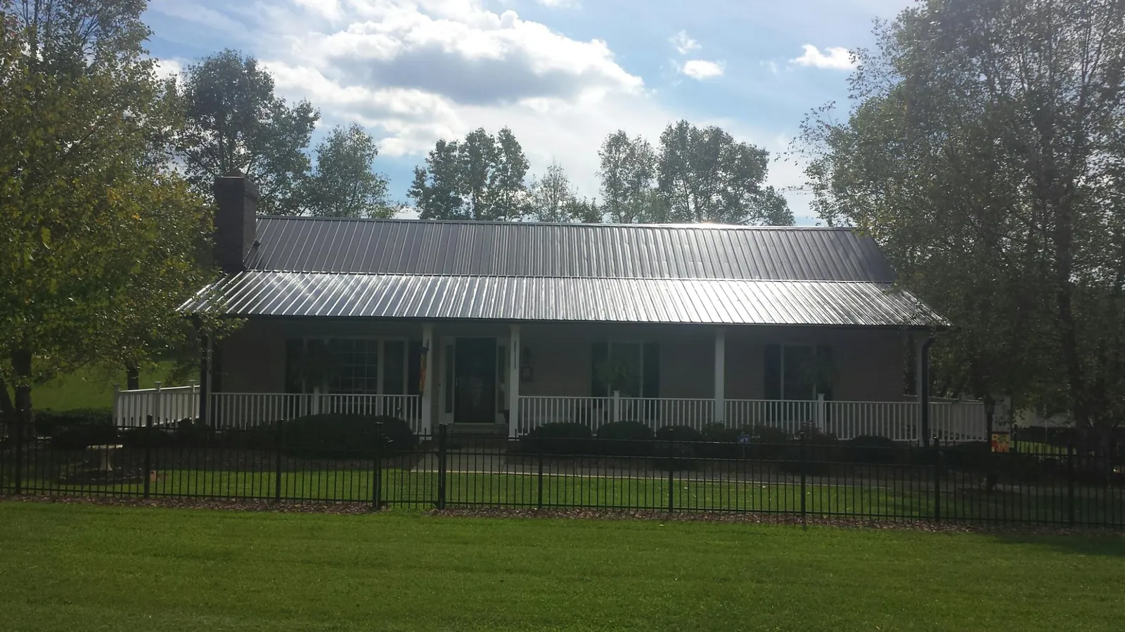 Gray metal roof on a brick ranch with a full width front porch — Gutter Guard Installation work by our crew in Stanley
